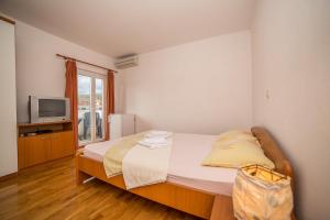 a small bedroom with a bed and a television at Villa Albatros in Vinišće