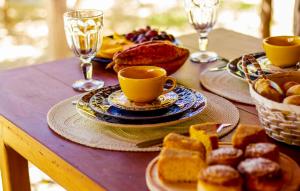 a table with plates and cups of coffee and pastries at Pousada Cajuzinho do Cerrado in Cavalcante +19 photos