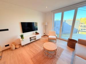 a living room with a flat screen tv and a large window at Le Loft des Crêtes in Dinant