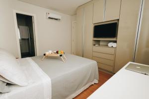 a bedroom with two beds and a tv and a table at LRFlat 3 - Flat para pessoas exigentes com requinte e conforto próximo de tudo! Garagem e portaria 24h in Montes Claros +33 photos