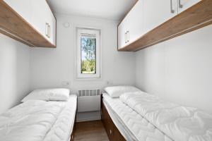 two beds in a room with a window at First Camp Lunde - Telemark in Lunde