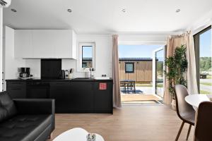 a kitchen and living room with a black couch at First Camp Lunde - Telemark in Lunde +9 photos