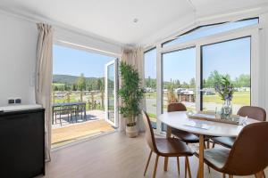 a living room with a table and chairs and a large window at First Camp Lunde - Telemark in Lunde