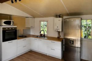 a kitchen with white cabinets and a stainless steel refrigerator at Le Mas de L intention La Class Act in La Crau