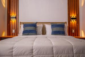 a large white bed with two blue pillows on it at Tribe Boutique Resort by Mega Stays in Guayacanes