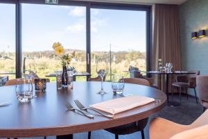 ein Esszimmer mit einem Tisch und Weingläsern in der Unterkunft Fletcher Hotel - Restaurant Elzenduin in Ter Heijde