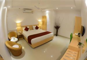 a bedroom with a bed and a chair in a room at Hotel Anantha Suites in Sitam Petta