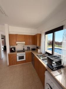 a kitchen with wooden cabinets and a large window at Casa Elea in Kouklia