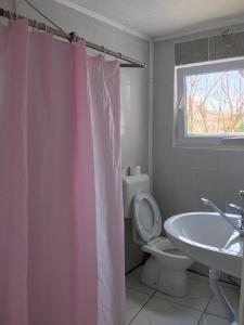 a bathroom with a pink shower curtain and a toilet at Guest House LEA in Mostar