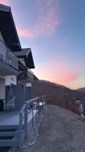 a house with a deck with a sunset in the background at Amaretto Apartamenty Solina centrum in Solina