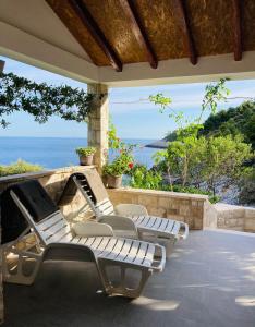a row of lounge chairs on a patio with the ocean at Contessa robinson house in Korčula