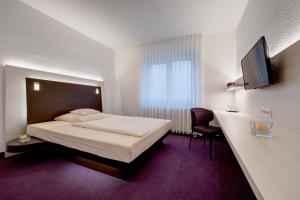a hotel room with a bed and a tv at Hotel-Restaurant Öhlers in Hannover
