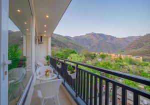 a balcony with a table and chairs and mountains at Alpine Retreat in Narendranagar
