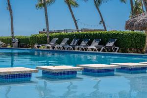 a swimming pool with chairs and palm trees at Tribe Boutique Resort by Mega Stays in Guayacanes