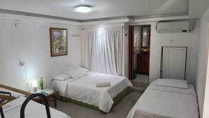 a bedroom with two beds and a table and a window at Hostal Casa de las Americas in Cartagena de Indias