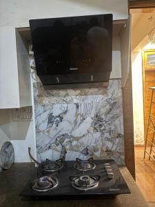 a stove top in a kitchen with a tv on the wall at Karshni Kuteer in Mathura +9 photos