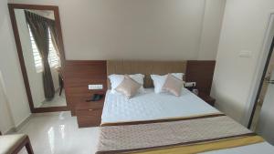 a bedroom with a bed with pillows and a mirror at COMFORT Inn in Subrahmanya