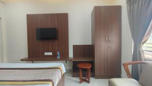a bedroom with a bed and a desk with a television at COMFORT Inn in Subrahmanya +7 photos