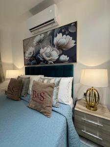 a bedroom with a blue bed with a painting on the wall at B&S Accommodation Newly Renovated Penthouse 253 in Żejtun