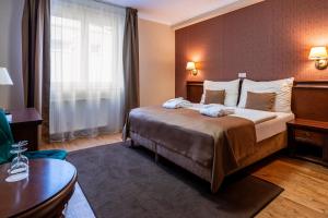 a hotel room with a large bed and a table at Wellness Hotel Pivovar Monopol in Teplice