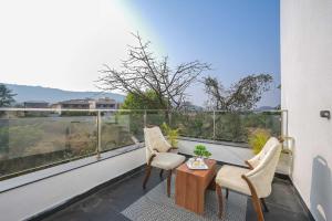 a balcony with two chairs and a table and a window at 6BHK White Castle Villa in Malavli