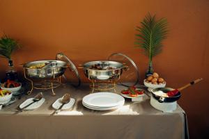 a table with two pots and plates of food at Kulala Stays Lodge in Livingstone