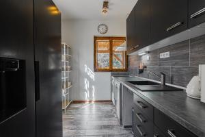 a kitchen with black cabinets and a sink and a window at Villa Pontis Rabštejn nad Střelou in Rabštejn nad Střelou +43 photos