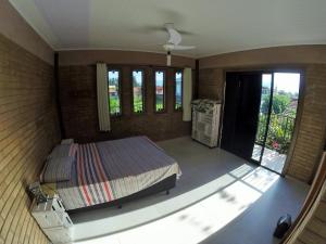 a bedroom with a bed and a balcony with windows at Morada das Flores in Palhoça