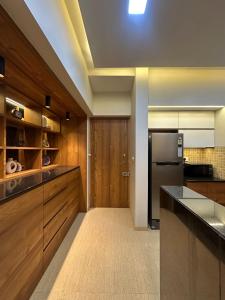 a large kitchen with wooden cabinets and a refrigerator at Skyline Serenia 23rd floor in Dehu Road