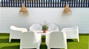 a room with white chairs and a table with a plant at Casa Alegra Pool & Spa in Gran Alacant
