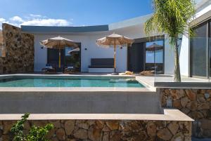 a swimming pool with umbrellas in a house at Orama Estate in Koskinou