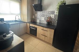 a kitchen with black counters and a black refrigerator at Rayon de vacances T3 spacieux et bien équipé in La Possession