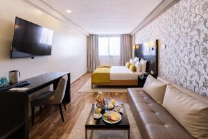 ein Hotelzimmer mit Sofa und Bett in der Unterkunft Hôtel du Golf Mohammedia in Mohammedia
