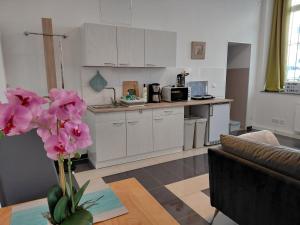 a kitchen with white cabinets and a vase with pink flowers at Ferienwohnung CityImmo in Gotha