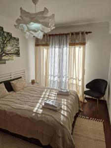 a bedroom with a large bed and a black chair at LandS in Caniço