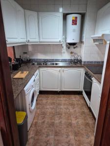 a kitchen with white cabinets and a washer and dryer at LandS in Caniço +3 photos