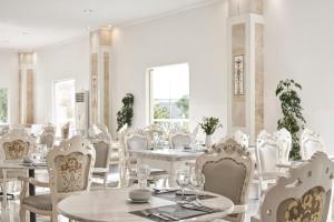 a dining room with white tables and chairs at Sandy Beach Resort by Rizos Resorts in Agios Georgios +74 photos