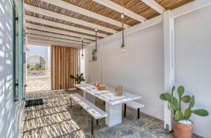a dining room with a table and a bench at Villa Paros Spiti Mataki in Aliki