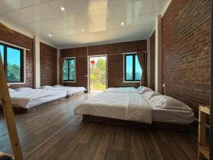 a bedroom with two beds and a brick wall at De Pakha Homestay in Bắc Hà