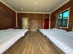two beds in a room with a brick wall at De Pakha Homestay in Bắc Hà