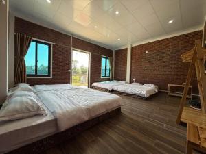 a bedroom with two beds and a brick wall at De Pakha Homestay in Bắc Hà