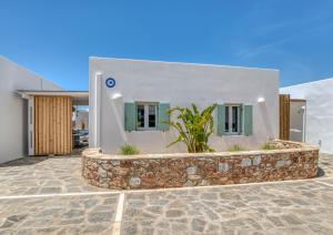 a white house with a stone wall in front of it at Villa Paros Spiti Mataki in Aliki