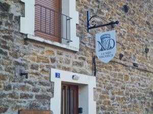a brick building with a door and a sign on it at Le Nid Daudèce in Le Châtelet-sur-Sormonne