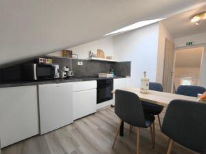 a kitchen with white cabinets and a table with chairs at Apartment Juliet in Izola