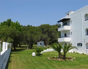 a white building with a grass yard next to a building at Maistrali Studios Skiathos in Koukounaries