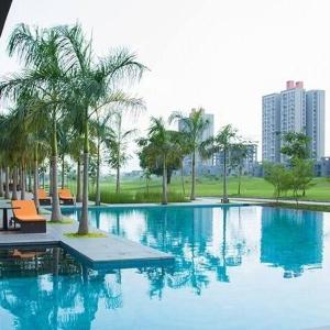 a large swimming pool with palm trees in a city at Serene white studio - 2nd floor in Dehu Road
