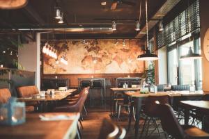a restaurant with tables and chairs and a map on the wall at Fliegerdeich Hotel & Restaurant in Wilhelmshaven