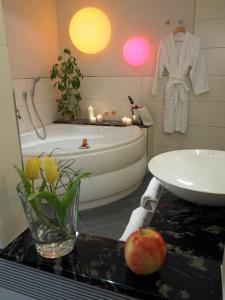 ein Badezimmer mit einer Badewanne, einem Waschbecken und einem Apfel auf der Theke in der Unterkunft Landhotel Mühle zu Gersbach in Gersbach