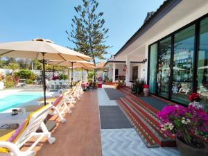 a pool with chairs and umbrellas next to a building at Celine Pool Villa Cha-Am in Cha Am