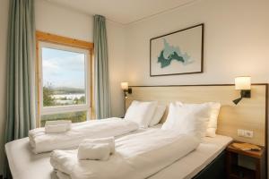 two beds in a hotel room with a window at Center Parcs Bostalsee Saarland in Nohfelden +65 photos